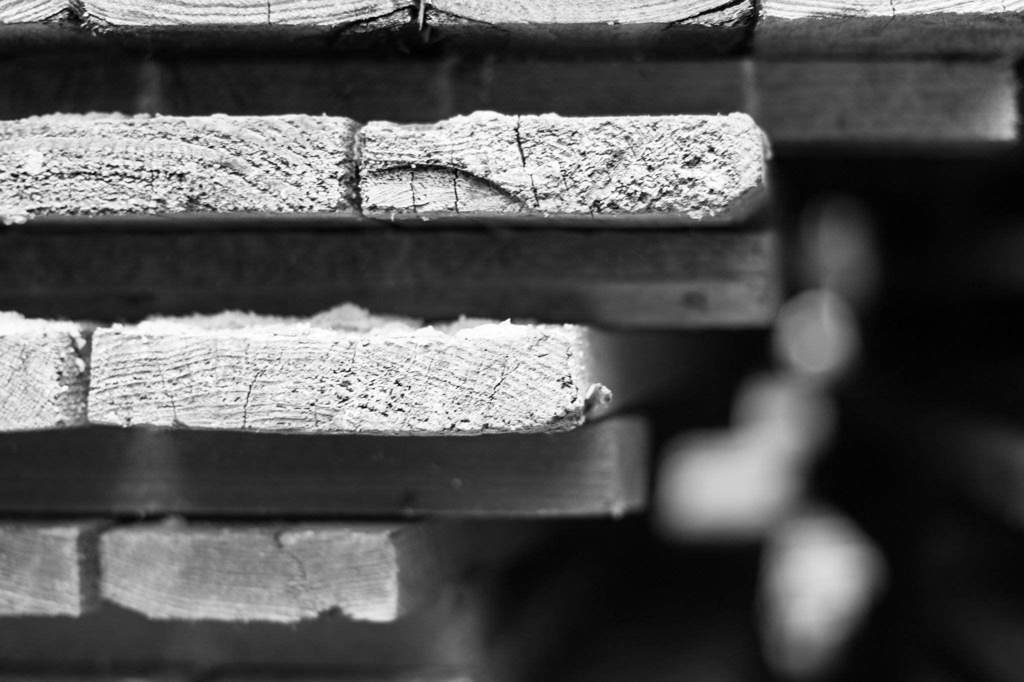 Detailed black and white photo showcasing stacked wooden planks with textured surfaces.